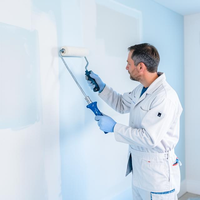 Professional painter rolling fresh paint onto an interior wall
